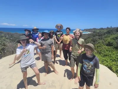 Underwood Scouts posing together on a sand dune on North Stradbroke Island/Mineeribah with the ocean in the background