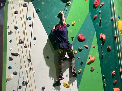 Underwood Venturer Scout climbing an indoor rock climbing wall wearing a harness